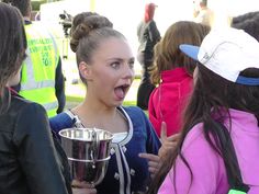 a woman holding a trophy in front of her face while standing next to other people