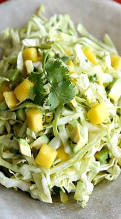 a white plate topped with coleslaw and mango