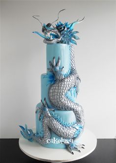 a three tiered blue cake with silver dragon decorations