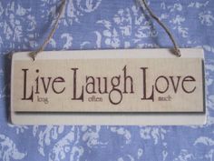 a sign that says live laugh love hanging on a blue and white fabric wallpaper