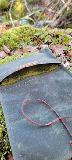 an old book is laying on the ground covered in moss and grass with a red cord