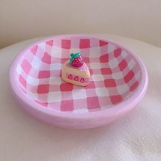 a pink and white checkered plate with a small piece of cake on the edge