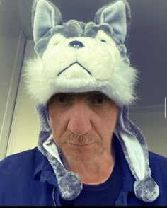 an older man wearing a hat with a dog on it's face and ears