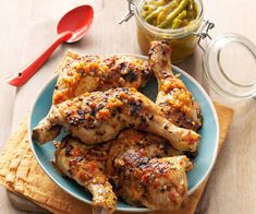 a plate full of chicken and green beans on a wooden table next to a jar of pickles