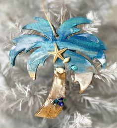 a christmas ornament with a palm tree and starfish hanging from it's side