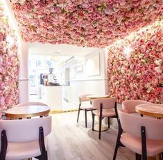 the interior of a restaurant with pink chairs and flowers on the wall behind them,