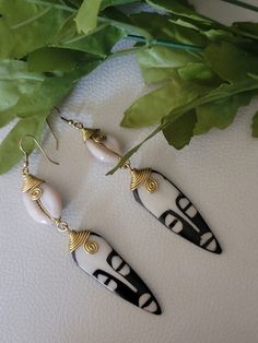 Introducing our exquisite bone mask Cowrie Shell Brass Earrings, the perfect embodiment of elegance and cultural essence. Handcrafted with utmost care and attention to detail, these earrings are a true fusion of tradition and contemporary style. Each earring features a well known face or mask and a cowrie shell, intricately encased in a delicate brass frame. The cowrie shells, renowned for their significance and symbolism in various African cultures, bring a sense of authenticity and charm to these earrings. Their natural, pearlescent sheen gracefully catches the light, capturing attention and adding a touch of mystique to any ensemble. 🖤Note: Each pair of earrings is individually handcrafted, and due to the natural variations of cowrie shells, slight differences in color and shape may oc Traditional Bone-colored Jewelry As A Gift, Traditional Bone-colored Jewelry Gift, Elegant Handmade Bone-colored Jewelry, Bohemian Bone-colored Pierced Earrings, Bohemian Bone-colored Earrings, White Artisan Earrings For Pierced Ears, Handmade Adjustable Bone Colored Earrings, Handmade Artisan Bone-colored Jewelry, Unique White Brass Earrings