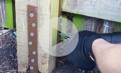 a person is holding a drill in their hand near a wooden fence with screws on it