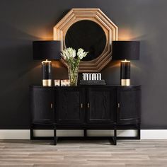 a black and gold sideboard with a mirror on the wall next to two lamps