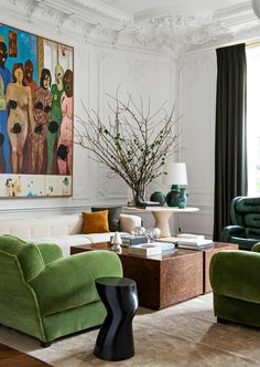 a living room with two green chairs and a painting on the wall above it's fireplace