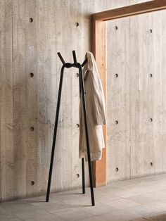 a coat rack with two coats hanging on it's sides and a white shirt hanging from the top