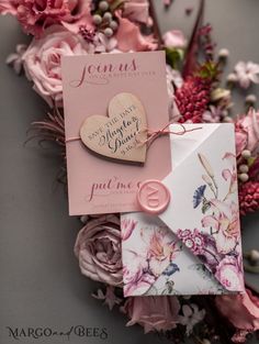 a pink and white wedding stationery with flowers on it, including a heart - shaped card