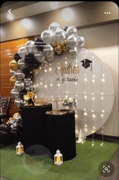 an arch made out of balloons and some black and white decorations on the ground with lights