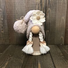 a doll with braids and a flower on it's head sitting on a wooden surface