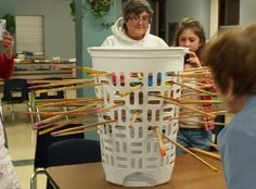 two girls and an older woman are looking at a basket with knitting needles in it