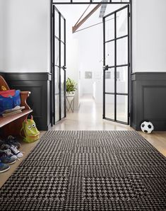 a black and white area rug in front of an open door with soccer balls on the floor