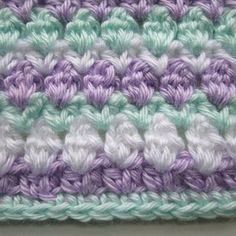 a crocheted blanket with white and purple stripes