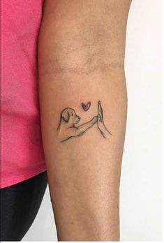 a woman's arm with a dog holding a heart tattoo on her left forearm