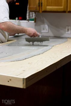 a man is working on some kind of project in the kitchen with wood and cement