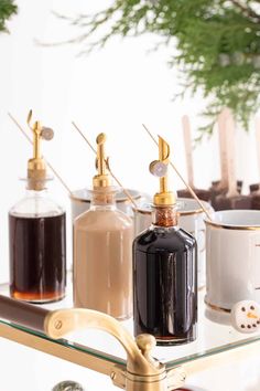 three different types of soap dispensers sitting on a glass shelf next to coffee mugs