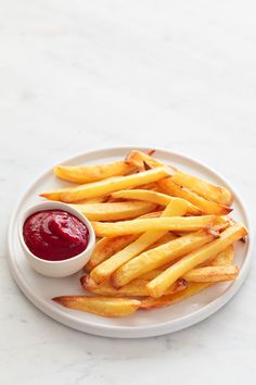 french fries on a plate with ketchup and mustard in a small white bowl