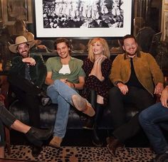 four people sitting on a couch smiling for the camera