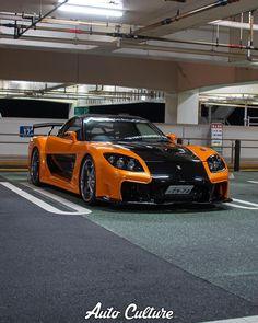 an orange and black sports car parked in a parking garage