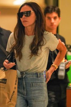 the woman is carrying her shopping bags while walking down the street with another man in the background