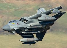 a fighter jet flying through the air with its landing gear down