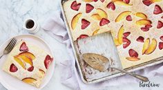 a cake with sliced peaches on it next to a cup of coffee and fork