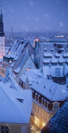 the city is covered in snow and has tall buildings with steeples on each side