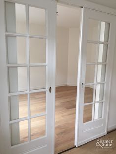 an empty room with white doors and wood floors