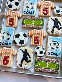 decorated cookies in the shape of soccer players and numbers are displayed on a plastic tray