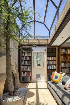 a living room filled with lots of furniture and bookshelves next to a tree