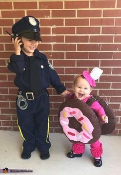 two children dressed up as police officers and one is holding a donut while the other holds a doughnut