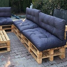 a couch made out of wooden pallets sitting on top of a brick patio area