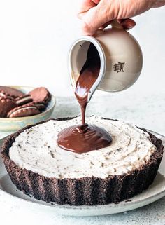 someone pouring chocolate sauce on top of a cake