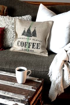 a coffee mug sitting on top of a wooden table next to a brown couch with pillows