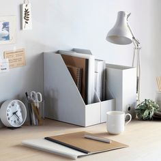 an office desk with a clock, pen holder and other items on the table next to it