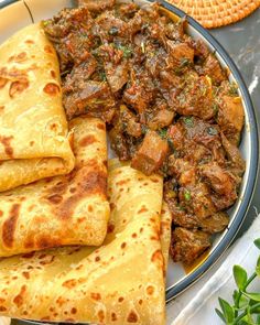 some food is on a plate with pita bread and other foods in the background