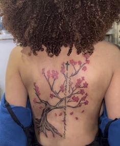 the back of a woman's upper body with tattoos on her chest and cross