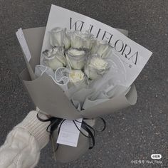 a bouquet of white roses wrapped in gray paper