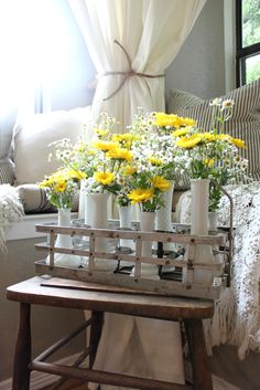 a wooden bench with vases filled with yellow and white flowers on top of it