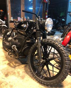 a black motorcycle parked in a garage next to other motorcycles