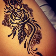 a black and white tattoo on the back of a woman's thigh with flowers