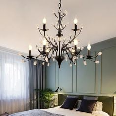 a chandelier hanging over a bed in a room with green walls and curtains