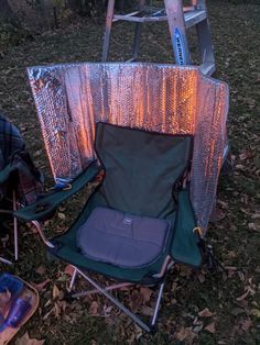 a folding chair sitting on top of a grass covered field next to a step ladder