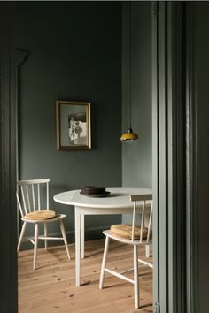 a white table and two chairs in a room with dark green paint on the walls