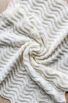 a white knitted blanket laying on top of a wooden floor