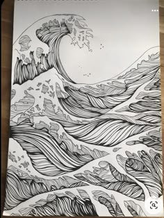 a drawing of an ocean wave in black and white on top of a wooden table